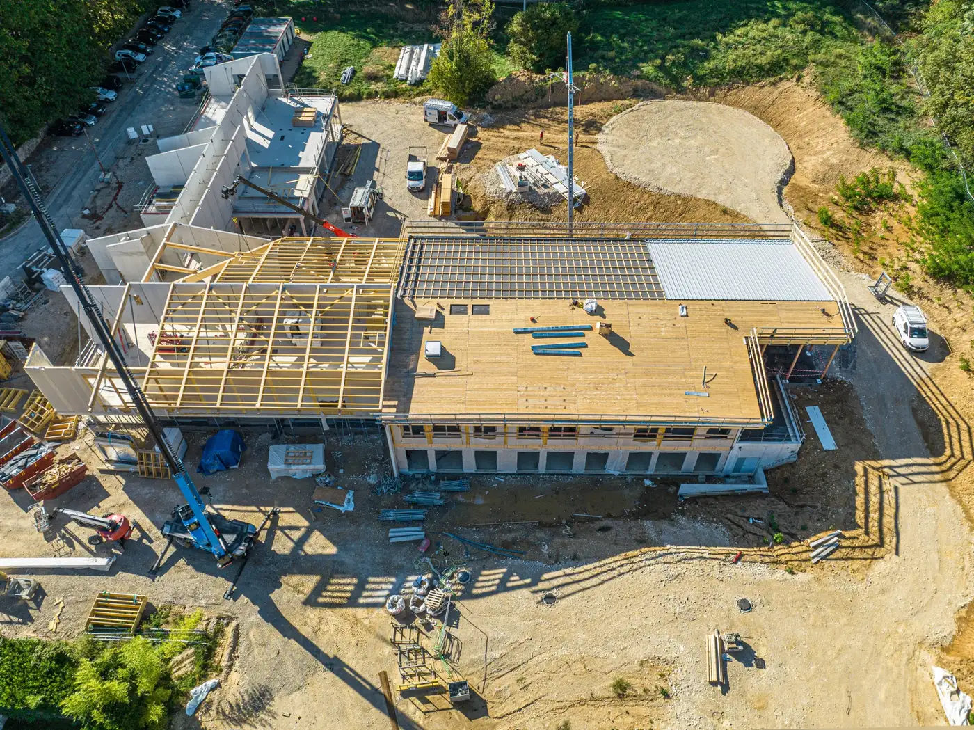 Le chantier du groupe scolaire de Pont-d'Ain vu du ciel : la charpente bois posée sur les murs du rez-de-chaussée, en septembre 2026
